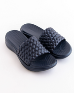 Pair of dark gray woven sandals on a white background